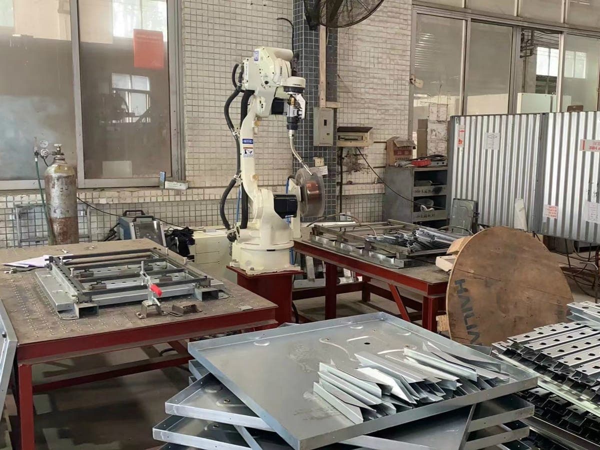 Braccio robotizzato di saldatura e componenti in lamiera piegata pronti per l'assemblaggio