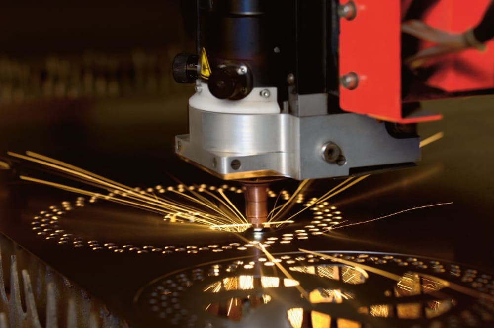 Testa di taglio laser fibra in lavorazione su lamiera d'acciaio, scintille incandescenti